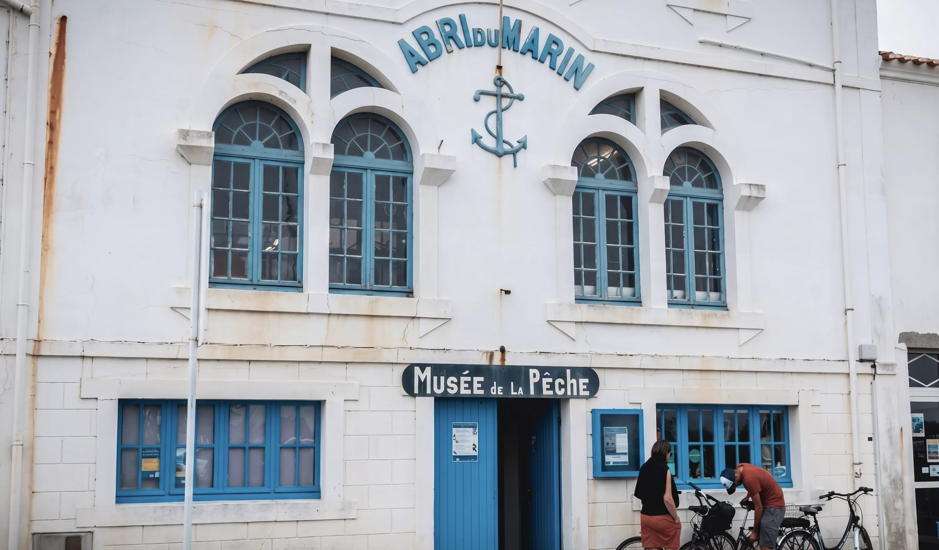 Façade blanche de l'Abri du Marin abritant le Musée de la Pêche à l'Île d'Yeu, avec ancre décorative et fenêtres bleues