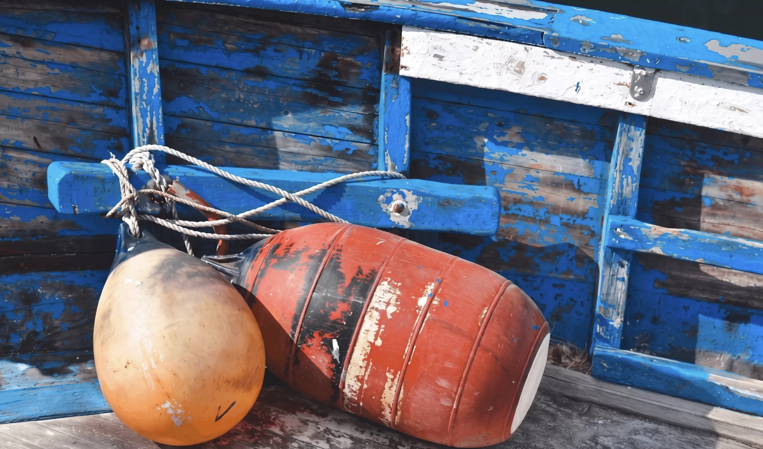 Bouées de pêche orange et rouge attachées à une barque en bois bleue traditionnelle dans un port de l'Île d'Yeu, Vendée