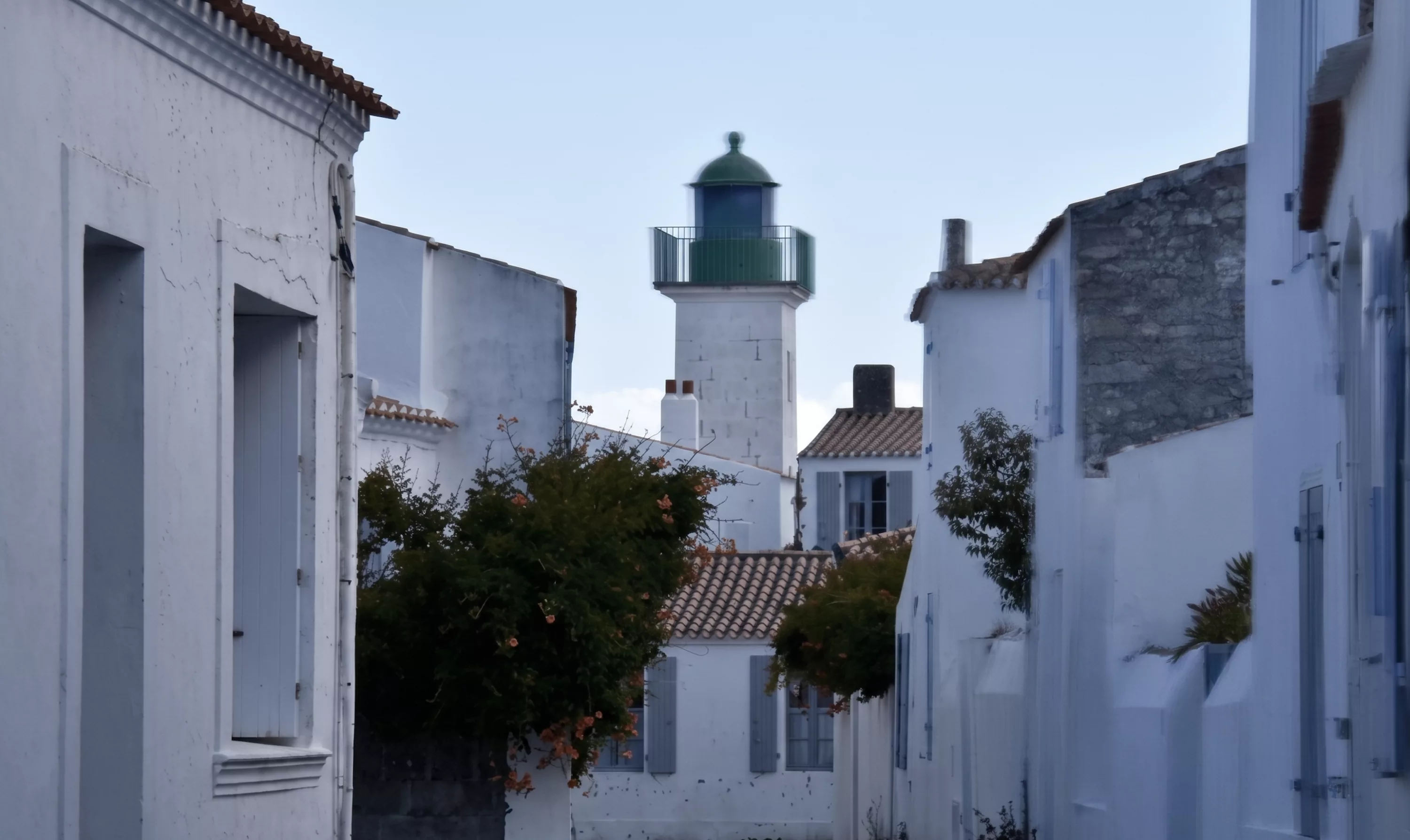Phare blanc émergeant au-dessus des ruelles et maisons blanches typiques du village de Port-Joinville, Île d'Yeu, Vendée
