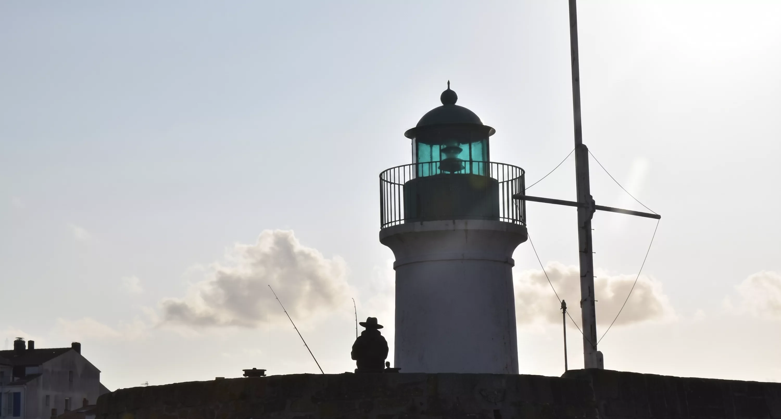 Silhouette d'un pêcheur devant le phare de la Petite Foule au coucher du soleil sur l'Île d'Yeu