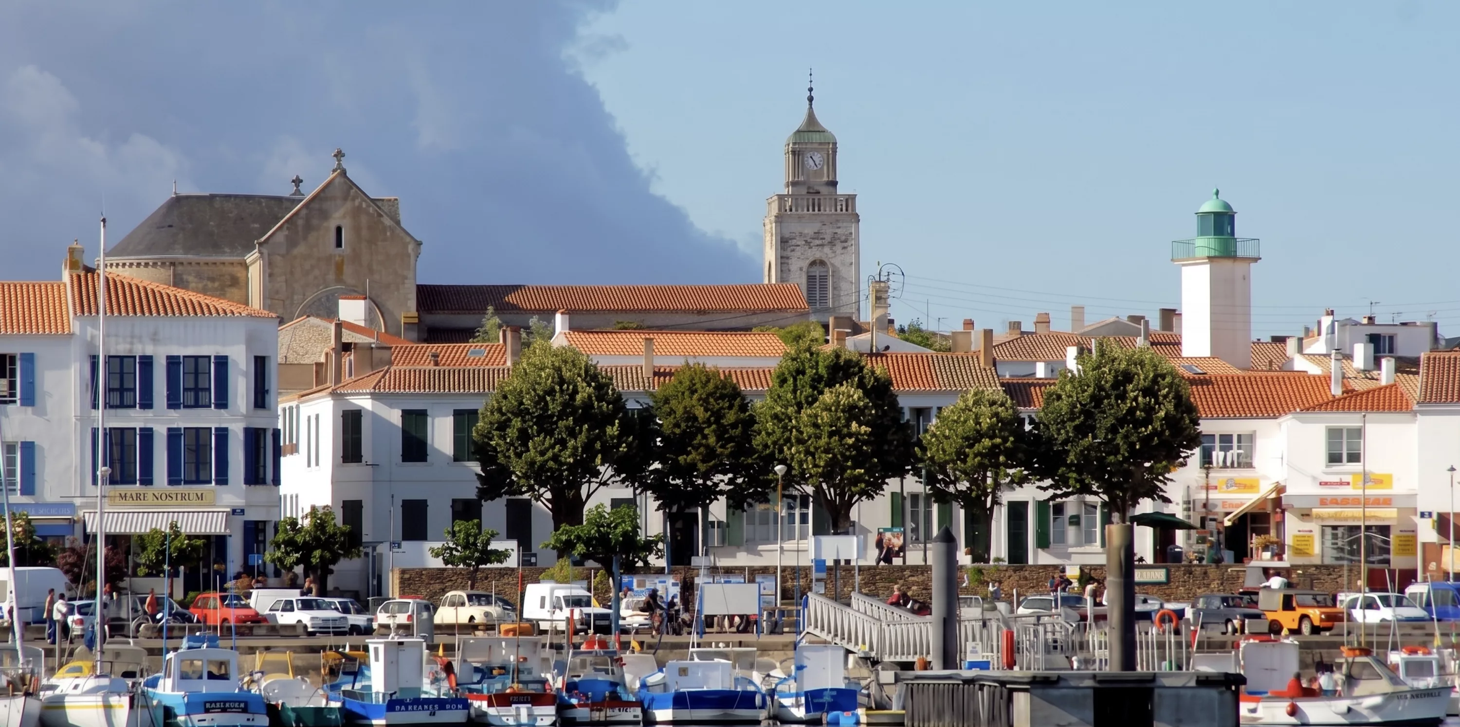 Port de Port-Joinville sur l'Île d'Yeu avec ses maisons blanches aux toits de tuiles, le clocher de l'église et le phare vert