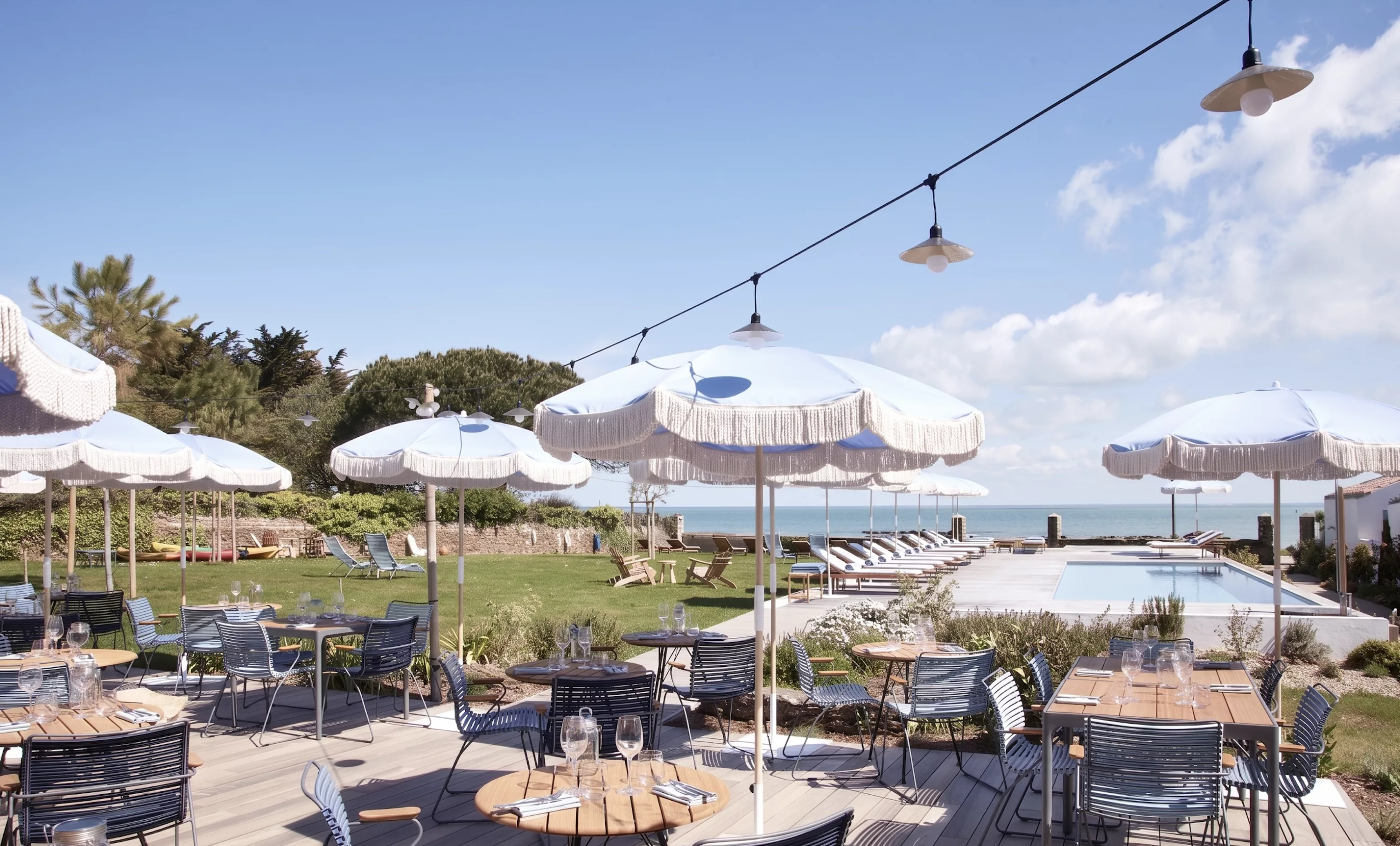 Terrasse du restaurant les Hautes Mers, avec parasols blancs, chaises bleues et piscine face à la mer sur l'Île d'Yeu en Vendée